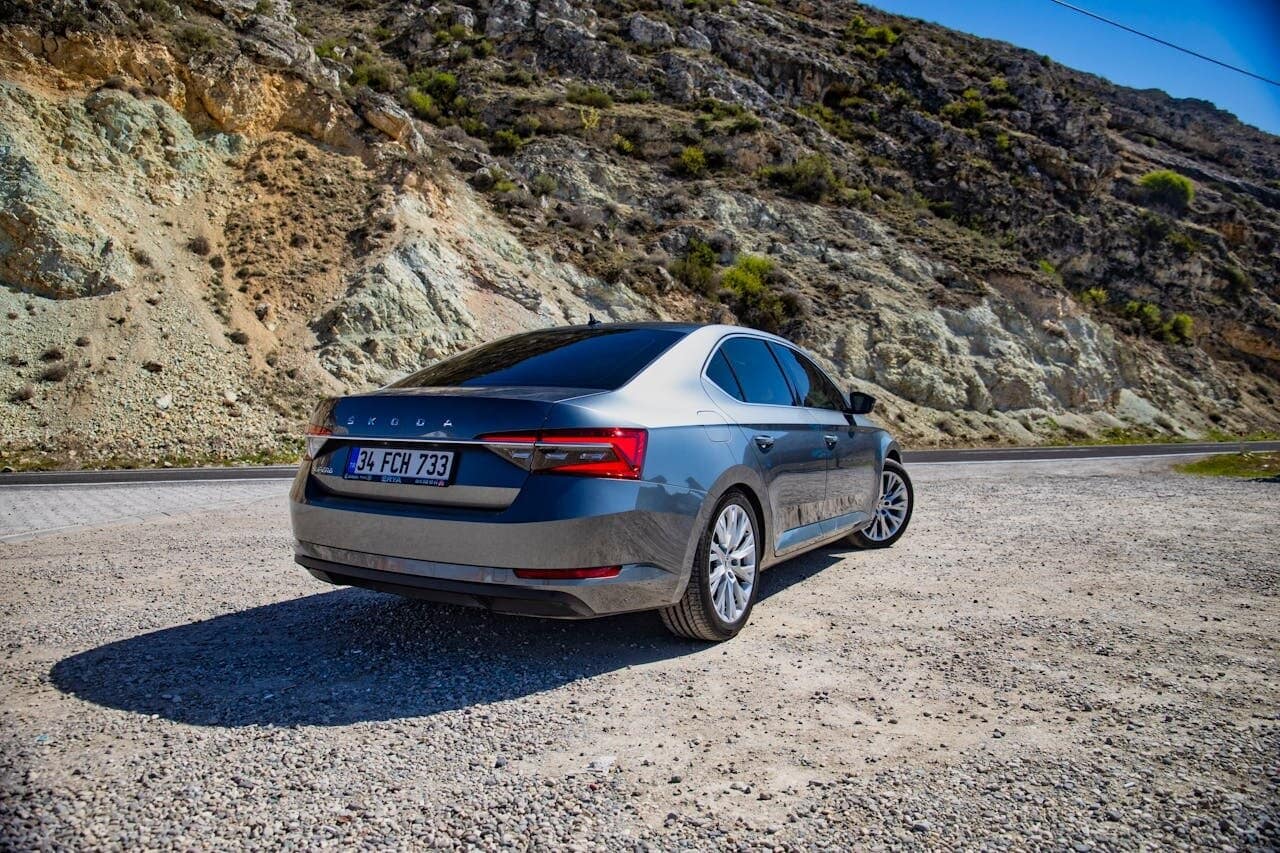 Skoda Superb parked on a gravel road next to rolling hills