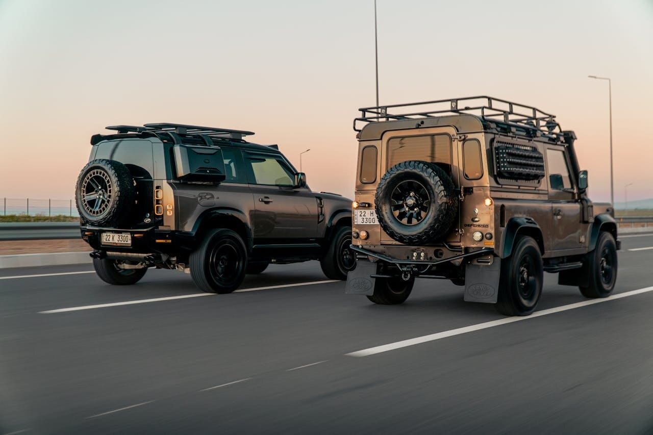 Two Land Rover Defender vehicles leaving the city for a road trip